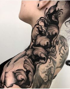 a woman's neck is covered in black and grey ink with an intricate design