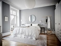 a bedroom with gray walls, white bedding and wooden floors is pictured in this image