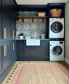 a washer and dryer in a laundry room with blue cabinets, rugs and wallpaper