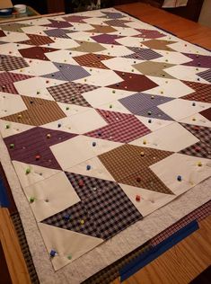 a large quilt is laying on top of a wooden table in the middle of a room