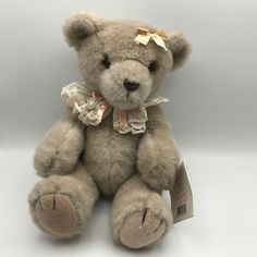 a brown teddy bear with a tag on it's collar and bow around its neck