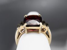 This beautifully structured vintage mounting holds a bold stone! This gem is a gorgeous deep red garnet, weighing in at nearly 10 carats. Garnets are known for their exceptional color and play of light, and this gem is opulent and sophisticated. Metal: 10K Yellow Gold Gem: Garnet 9.88 Carats Gem Measurements: 10.5 x 13.4 mm, Rectangle Cushion Cut Ring Size: 6.25 Marks: "10K" Stamped on the inside band Formal Garnet Burgundy Ring, Formal Burgundy Garnet Ring, Formal Garnet Ring With Polished Finish, Classic Burgundy Ruby Ring For Formal Occasions, Elegant Large Stone Ruby Ring Gift, Elegant Ruby Ring With Large Stone For Gift, Formal Burgundy Gemstone Jewelry, Classic Formal Burgundy Rings, Elegant Ruby Jewelry With Large Stone