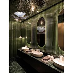 a bathroom with two sinks and mirrors in the wall, along with lights on the ceiling