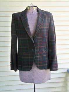 "This well-made vintage 1980s classic blazer is made of Dark Charcoal heavy weight Wool/Poly Blend fabric. The actual fabric is a darker grey than the photos, more like the close up. There are Turquoise, Red and Gold lines making a plaid on the dark charcoal background. This well-tailored jacket with curved and notched lapels closes with 1 button. It has a slightly cut away front at the bottom. The blazer has 2 pockets  in front. The sleeves are long. This jacket is fully lined, including the sl Fitted Vintage Sport Coat For Work, Retro Fitted Sport Coat For Fall, Fitted Retro Sport Coat For Fall, Fitted Retro Tweed Jacket For Winter, Retro Fitted Blazer For Fall, Fitted Retro Blazer For Fall, Tailored Vintage Blazer For Fall, Fitted Vintage Winter Sport Coat, Vintage Fitted Blazer For Fall