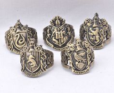 five different types of rings with crests on the front and back, set against a white background