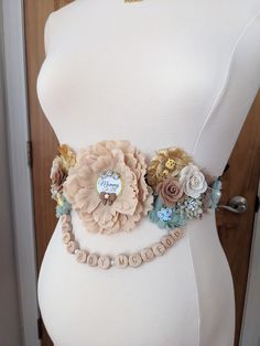 a white mannequin with flowers on it's waist and name tag attached to the belt