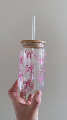 a hand holding a glass with pink bows on it