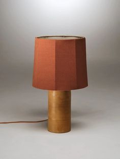 a table lamp with a red shade on it's side and a cord plugged into the base