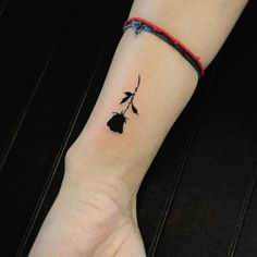 a small black flower tattoo on the wrist