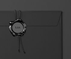 a black envelope with a waxed seal and string tied around the front pocket, on a dark background