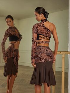 two women in brown and black outfits standing next to each other on a wooden floor