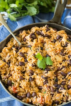 mexican rice and beans in a skillet with cilantro garnishes