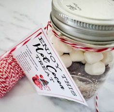 a jar filled with white and red candy canes next to a twine of twine