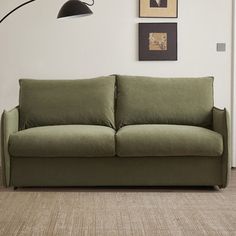 a green couch sitting on top of a hard wood floor next to a white wall