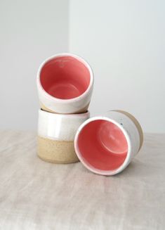 two white and red bowls sitting on top of a table