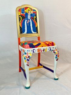 a colorful painted wooden chair sitting on top of a white sheet