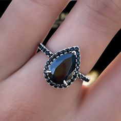 a woman's hand with a black diamond ring on top of her finger,