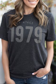 a woman wearing a vintage 1970 t - shirt with the number 799 printed on it