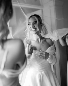 a woman in a wedding dress smiles as she fixes her veil