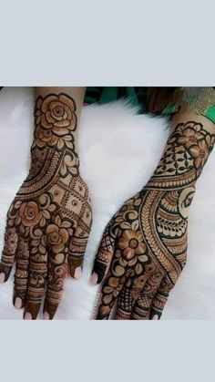 two hands with henna tattoos on them, one is showing off the intricate design