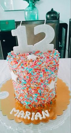 a birthday cake with sprinkles and the number twelve on it is displayed