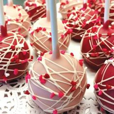 chocolate covered cake pops with white icing and sprinkles on a table