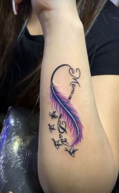 a woman's arm with a tattoo on it that has a pink and blue feather