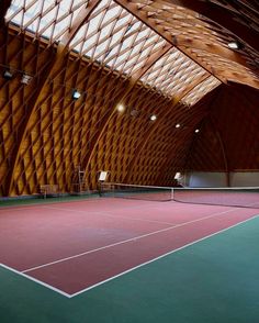 an indoor tennis court with wooden walls and ceilinging is seen in this image from the inside