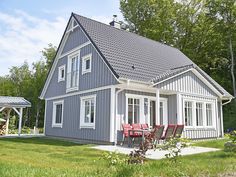 a gray house with red chairs in the front yard