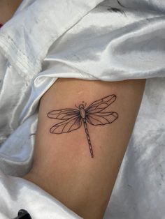 a small dragonfly tattoo on the back of a woman's thigh