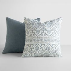 two blue and white pillows sitting on top of each other