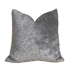 a gray and white pillow with black spots on the front, sitting against a white background