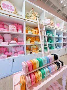 there are many items on the shelves in this store that is filled with pink, blue, yellow and green