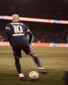 a man kicking a soccer ball on top of a field