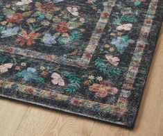 an area rug with flowers and leaves on the floor in front of a wooden floor