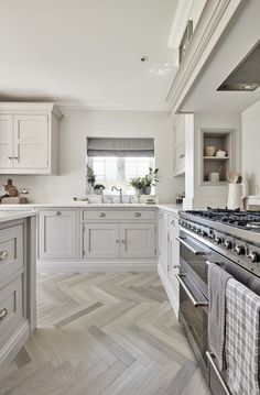 a large kitchen with white cabinets and wood flooring, along with stainless steel appliances