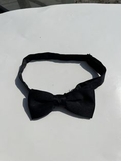 Up for sale is a vintage black pre-tied adjustable bowtie. Perfect for black tie.  The tie is in good used condition, and there is no obvious damage.  Please contact me with any questions! Dapper Adjustable Bow For Black Tie Events, Adjustable Dapper Bow For Black Tie Events, Classic Bow Tie For Black Tie Events, Dapper Tie With Butterfly Knot For Black Tie Events, Adjustable Butterfly Knot Bow Tie For Black Tie Events, Adjustable Black Bow For Black Tie Events, Adjustable Dapper Tie For Black Tie Occasions, Black Adjustable Suit And Tie Accessories With Satin Bow, Adjustable Bow Tie For Black Tie Events