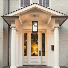 the front entrance to a white house with columns