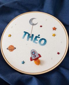 a hand embroidered wall hanging with the word thieo written on it and various space related items