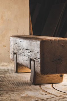 a wooden bench sitting on top of a floor next to a wall with wood planks