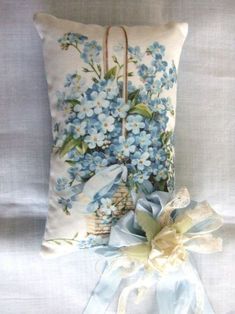 a blue flowered pillow sitting on top of a bed next to a white bag