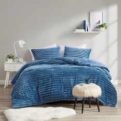 a bedroom with a blue comforter and white fur rugs on the wooden floor