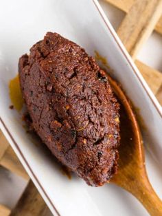 a piece of chocolate cake sitting on top of a white plate with a wooden spoon