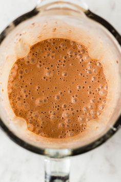 a blender filled with brown liquid on top of a white counter