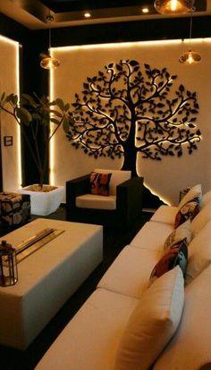 a living room with white couches and a tree on the wall