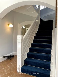 a blue carpeted staircase leading up to the second floor in a home with an arched doorway