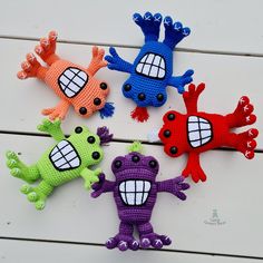 four crocheted toy monsters sitting next to each other on a white table top