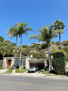 a car parked in front of a house with palm trees on the side of the road