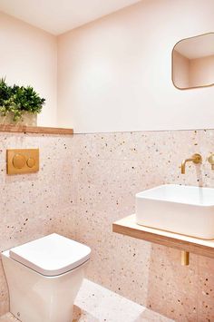 a white toilet sitting next to a sink in a bathroom under a wall mounted mirror