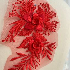 red flowers and leaves are embroidered on a white mannequin